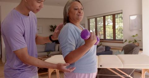 Physiotherapist Assisting Senior Woman with Arm Exercise at Home