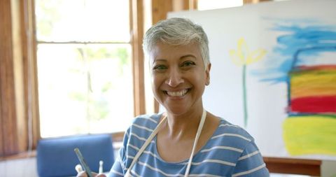 Joyful Senior Woman Enjoying Painting at Home in Bright Studio