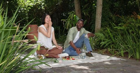 Couple Relaxing During Outdoor Picnic In Lush Garden