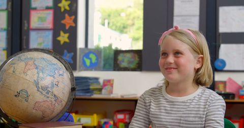 Smiling Schoolgirl Raising Hand in Geography Class
