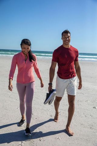 Fit couple walking on scenic beach enjoying outdoor fitness journey
