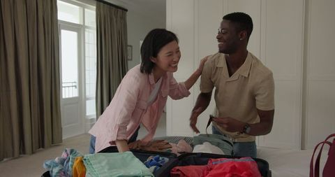 Couple Packing Clothes Together, Laughing in Bedroom
