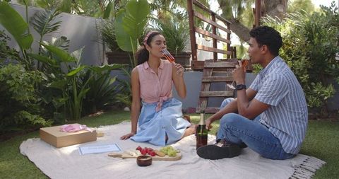 Couple Enjoying Picnic with Drinks in Tranquil Garden