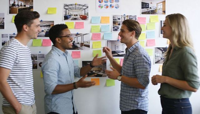 Creative team brainstorming with colorful sticky notes on office pinboard