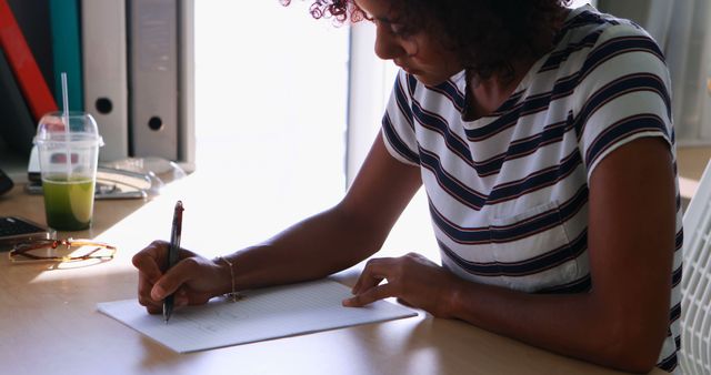 Focused Woman Writing at Desk with Papers and Folders - Download Free Stock Images Pikwizard.com