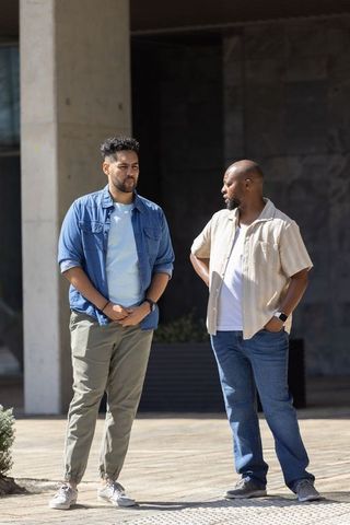 Two african american men talking outdoors in urban courtyard wearing casual denim