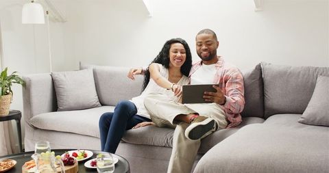 Excited couple sharing engagement news on tablet