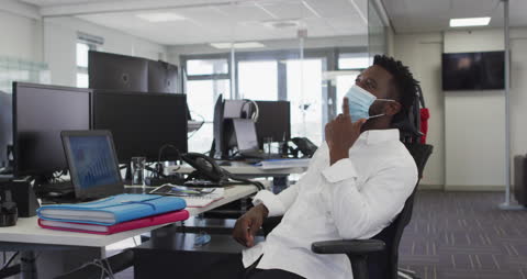 Focused Office Worker in Mask contemplating at Desk