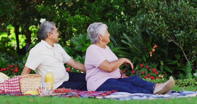 Image of happy biracial senior couple having picnic in garden. active retirement lifestyle, senior relationship and spending time together concept.