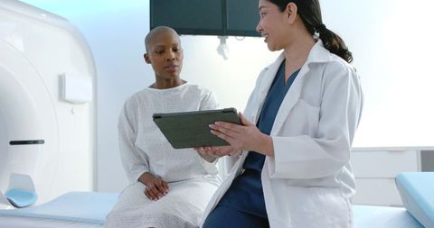 Clinician reviewing tablet with patient beside mri scanner in radiology consultation