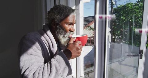 Man in Bathrobe Sipping Coffee by Sunny Window