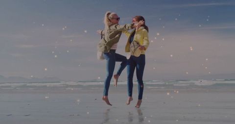 Joyful friends leaping at beach shoreline on sunny day