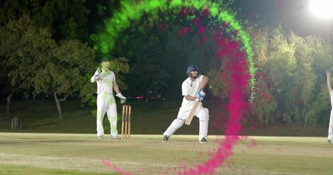 Night cricket batsman playing front-foot drive under floodlights with vibrant powder swirl