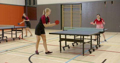 Athletic Women Playing Table Tennis in School Gym