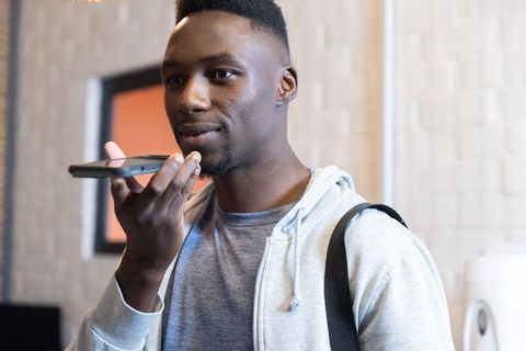 African american man speaking into smartphone in hallway wearing hoodie and backpack