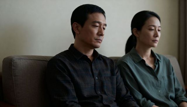Couple sitting in silent distance, contemplating relationship strain on sofa