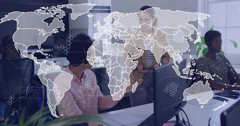 Diverse team collaborating around computers with global map overlay in open office