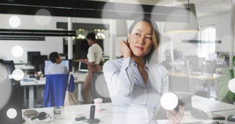 Thoughtful Businesswoman Holding Tablet in Modern Open-Plan Office
