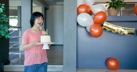 Senior Woman Celebrating Birthday with Cake and Balloons