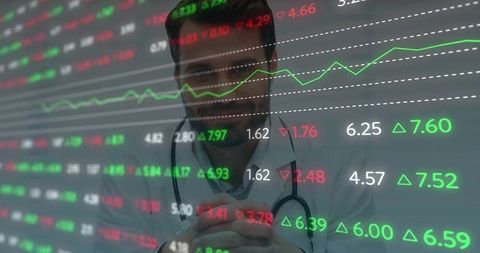 Physician reviewing financial charts and market tickers while wearing stethoscope