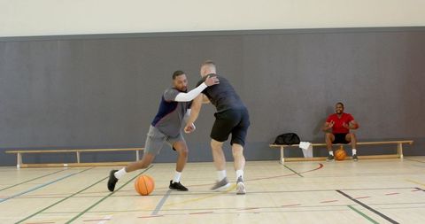 Fast-paced indoor basketball crossover dribble driving past defender on hardwood court
