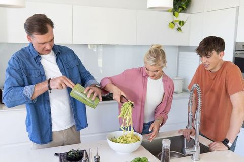 Family preparing green zoodles together in bright modern kitchen for healthy home cooking