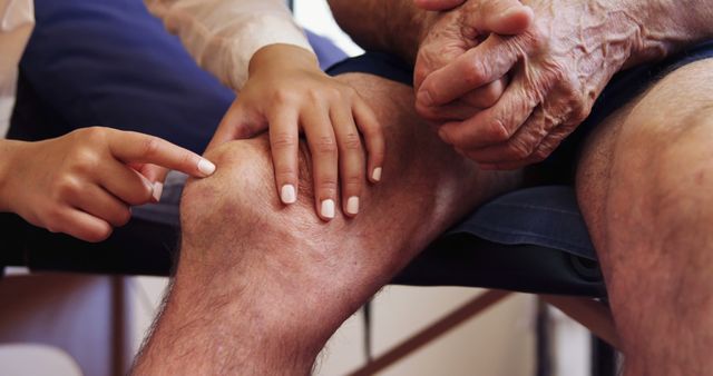 Healthcare worker examining an elderly person's knee, indicating potential medical care or physical therapy session. Useful for articles or presentations on elderly care, orthopedic health, medical studies, care for the aged, or doctor-patient interactions.