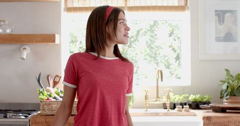 Woman in Cheerful Kitchen Gazing with Vegetable Basket and Potted Herbs
