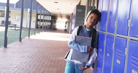 Thoughtful african american student by school lockers