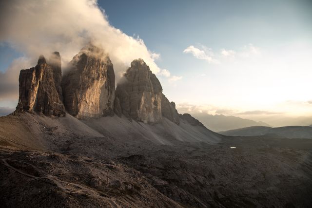 Beautiful view of the Tre Cime di Lavaredo peaks during sunset with clouds enveloping the peaks in the Dolomites, Italy. Ideal for travel publications, nature photography collections, scenic calendars, and advertising promoting adventure tourism and outdoor activities in mountainous regions.