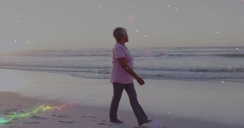 Senior Woman Walking Peacefully on Sandy Beach at Sunset