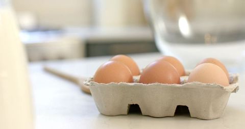 Brown eggs resting in recycled carton on bright countertop for minimalist kitchen prep