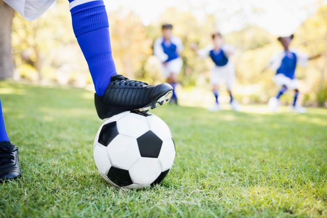 Close up view of balloon under football boots against children playing background in park