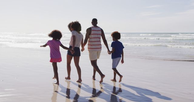 Family is walking hand-in-hand along the sandy beach by the ocean, enjoying a sunny day. Ideal for promoting family vacations, outdoor activities, and summer fun. Useful for travel brochures, family blogs, and lifestyle advertisements.