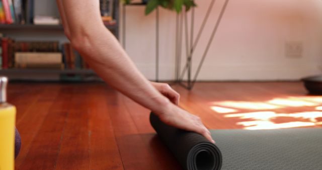 Person Rolling Up Yoga Mat on Wooden Floor - Download Free Stock Images Pikwizard.com