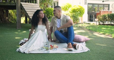 Couple enjoying picnic on blanket in sunlit garden