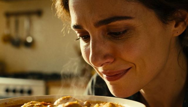 Young woman inhaling steam from homemade stew, closeup portrait embracing warm aroma