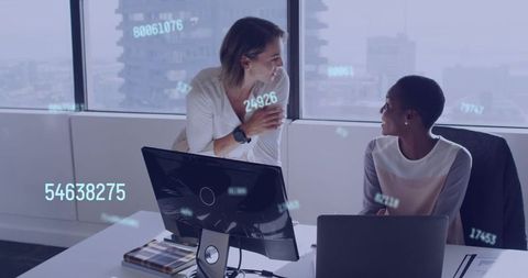 Women collaborating over analytics with holographic data overlays in modern office