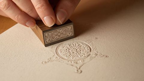 Pressing decorative embossed seal on cream paper for luxury wedding invitation stationery