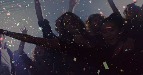 Dancing young adults under confetti in smoky nightclub, vibrant neon party atmosphere