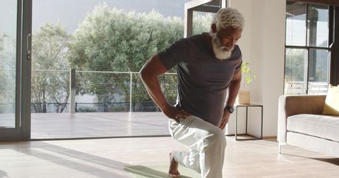 Senior Man Exercising on Yoga Mat in Sunlit Living Room