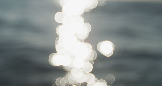 Abstract representation of sunlight reflecting off water creating a bokeh effect with blurry lights. Ideal for backgrounds, artistic designs, or concepts emphasizing tranquillity, light, and water elements.