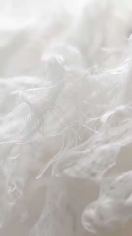Macro Vertical Video of White Fibers Drifting and Rotating Over Cream Textile Surface