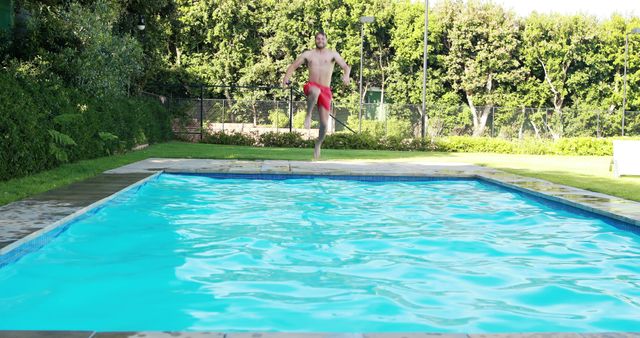 Man jumping into swimming pool on a sunny day