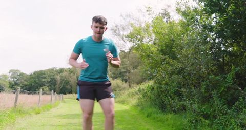 Man jogging on grass path in park embracing nature
