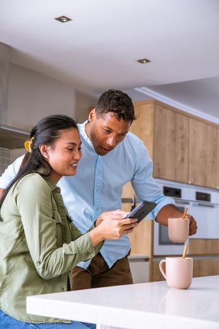 Happy Couple Enjoying Coffee and Smartphone Connection in Modern Kitchen