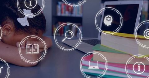 Weary student resting head on desk beside laptop and books with floating education icons