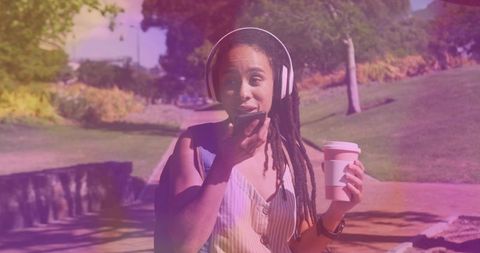 Woman Enjoying Music and Coffee on a Sunny Park Walk