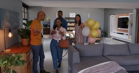 Friends welcoming guests with gifts and balloons for celebration