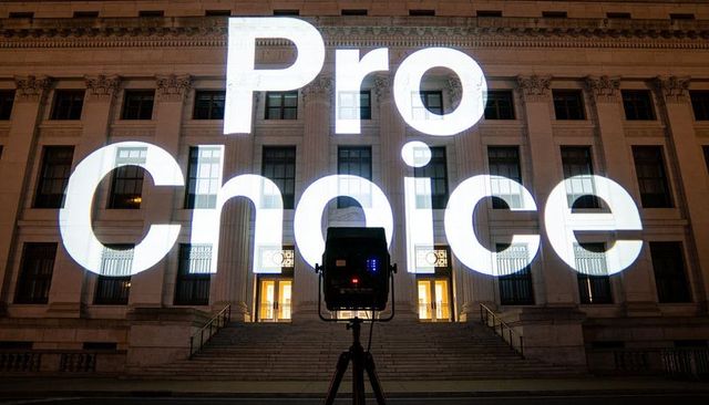 Projecting pro choice message on neoclassical civic building at night with tripod light